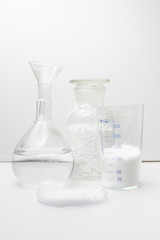 glass laboratory jar with samples of white synthetic rubber on a white background