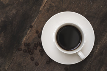 Cup coffee, roasted coffee bean on old wooden plate.