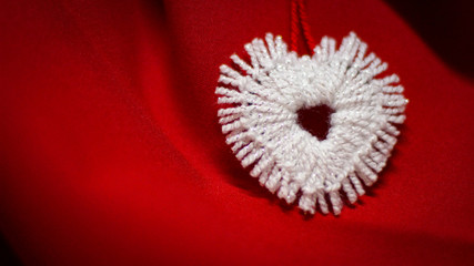 Beautiful white heart made of white thread on a red background