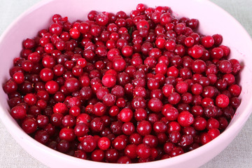 Frozen cranberry in pink plate on linen tablecloth