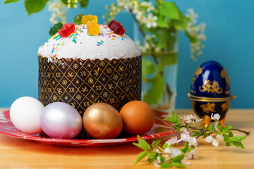 bird cherry branch next to easter cake and colorful easter eggs on wooden table