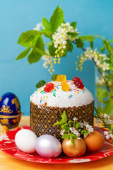 bird cherry branch next to easter cake and colorful easter eggs on wooden table