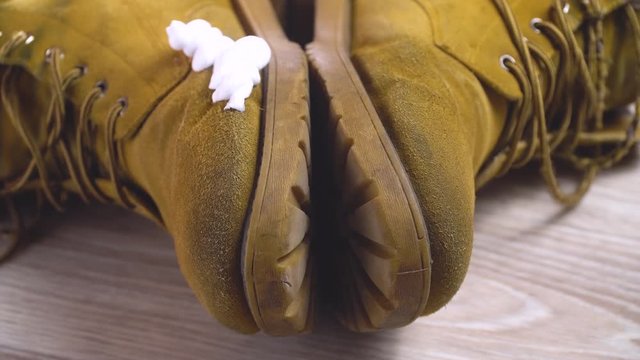Close-up man puts cleaning foam on dirty shoes from nubuk