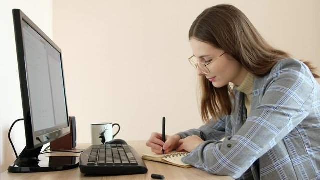 young woman in a jacket works at her workplace in front of a computer