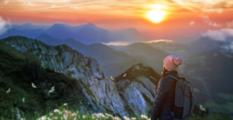 a girl with backpack in the top of the mountain at morning sunrise.