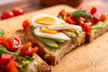 Mixed avocado toast with boiled eggs and tomatoes. Ideas for fast and nutritious dish. Summer food.