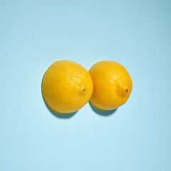 Two yellow lemons on a bright yellow background, imitation of a beautiful female breast.