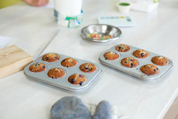 Confectioner took out freshly baked muffins in a baking dish on the table from the oven