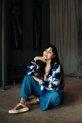 Obraz premium Portrait of smiling freedom woman sitting on the floor. Casual style indoor shoot.