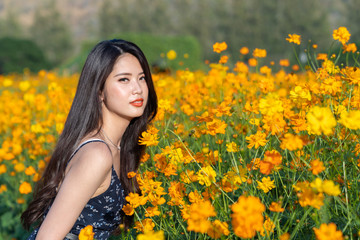 Asian cute young woman joyful, smiling with yellow cosmos background.
