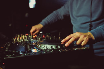 hands of dj are mixing tracks at party in night club. disc jockey playing music on the modern...