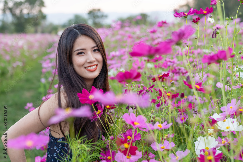 Wall mural asian cute young woman joyful, smiling with pink cosmos background.
