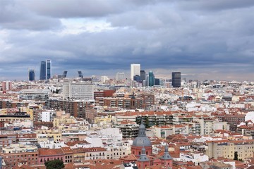Aerial panorama of the Madrid (Spain) skyline on a cloudy day, with the rooftops and domes of the old part of the city in the foreground and the skyscrapers of the financial zone in the background