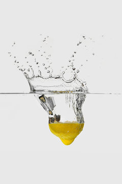 ripe yellow lemon hoop splashing into transparent water