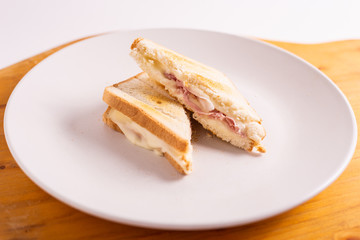 Ham and cheese toast served on a white plate. Fast and tasty snack.