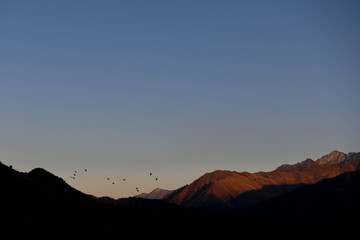The moon rises over a mountain lit by the setting sun in the Tusheti region.