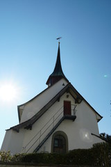 Old reformed church building in Urdorf, lateral view on a clear day with blue sky, the photo taken in upward perspective.