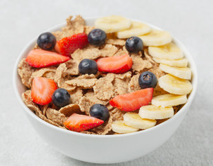 Multigrain wholegrain healthy cereal with banana and fresh berries strawberries and blueberries for Breakfast. Concept of delicious and healthy food.