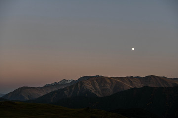 The moon rises over a mountain lit by the setting sun in the Tusheti region.