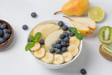 Healthy Breakfast smoothie in a bowl with banana, pear, kiwi, blueberry, lime and mint. The concept of healthy eating.