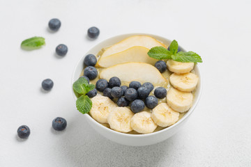 Healthy Breakfast smoothie in a bowl with banana, pear, kiwi, blueberry, lime and mint. The concept of healthy eating.