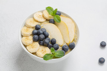 Healthy Breakfast smoothie in a bowl with banana, pear, kiwi, blueberry, lime and mint. The concept of healthy eating.