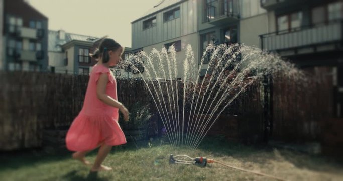 Uśmiechnięta dziewczynka bawi się w ogrodzie w upalny dzień.