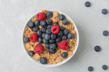 Multigrain wholewheat healthy cereals with fresh berry for breakfast. Bowl flakes with fresh berries raspberries and blueberries. 