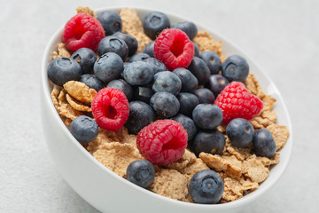 Multigrain wholewheat healthy cereals with fresh berry for breakfast. Bowl flakes with fresh berries raspberries and blueberries. Close up 