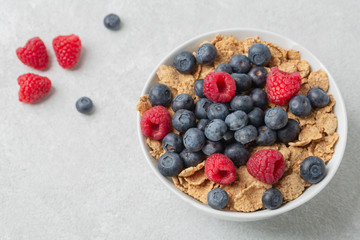 Multigrain wholewheat healthy cereals with fresh berry for breakfast. Bowl flakes with fresh berries raspberries and blueberries. 