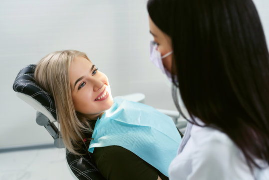 Dentist examining a patient's teeth in modern dentistry office. Closeup cropped picture with copyspace. Doctor in disposable medical facial mask.