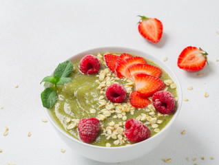 Breakfast green smoothie bowl with kiwi, banana, spinach, strawberries, raspberries and oatmeal. The concept of a detox diet.