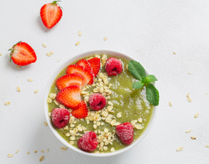 Breakfast green smoothie bowl with kiwi, banana, spinach, strawberries, raspberries and oatmeal. The concept of a detox diet.