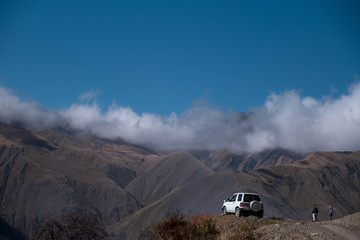 A off-road car is park in front of a landscape view of caucasus mountains in Georgia