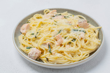 Spaghetti with salmon, cream cheese and spinach on plate. Italian cuisine. 