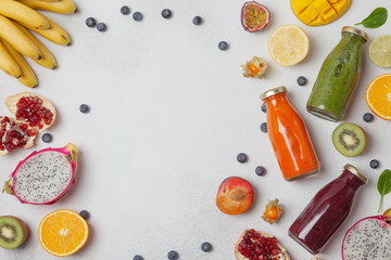 Assortment of colorful smoothies in bottles with fresh tropical fruit and vegetables, top view, space for text. Superfoods and health or detox diet food concept.