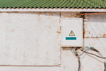 Electrical transformer box installed on the facade of white facade of the building. Electricity. Electrical wires. Warning sign. Power supply. Danger. Сommunications