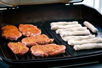Schweine-Steaks und Pizzaröllchen am Grill