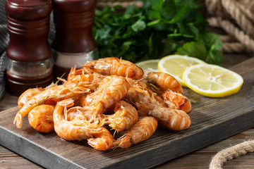 Shrimp on a wooden Board on a brown wooden table. Shrimp shrimps visor. Ecological seafood