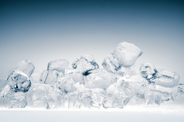 Heap of translucent crushed ice cubes on light blue background.