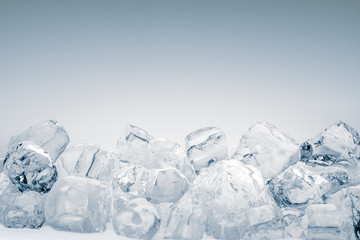 Heap of translucent crushed ice cubes on light blue background. Clipping path included.