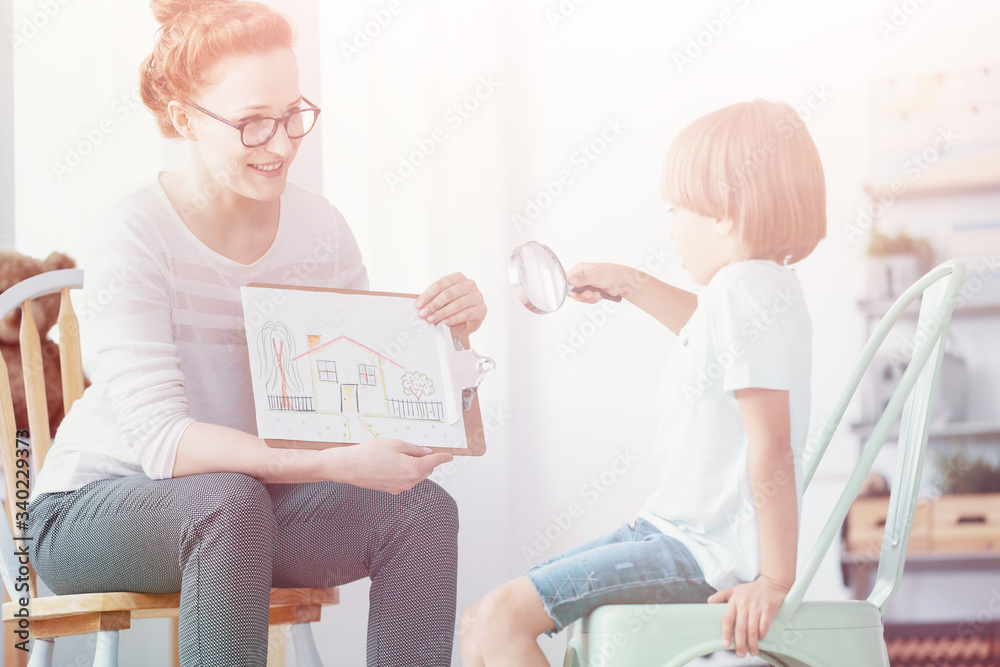 Wall mural smiling teacher with picture of house and boy with magnifying glass