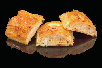 Pieces of traditional Bulgarian banitsa with white cheese. Black background