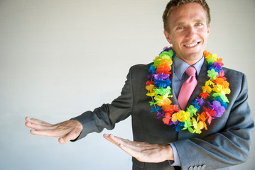 Smiling businessman dancing a happy hula dance wearing a colorful flower lei necklace