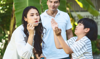 Asian family include father, mother and son playing the bubbles by blowing in happiness feeling together, park outdoor and house garden, warm family, home school, holiday and vacation togetherness,