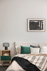 Abstract black oil painting in frame on empty beige wall of cozy bedroom