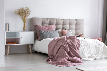 Grey king-size bed in pastel pink cozy bedroom
