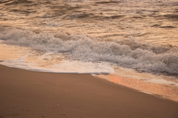 Natural background for text and sand and sea waves. Footprints in the sand from the legs go into the distance. Summer, sea, sunrise.