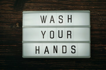 Wash Your Hands word in light box with space coy on wooden background