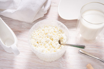 White cottage cheese in plastic jar on wooden table